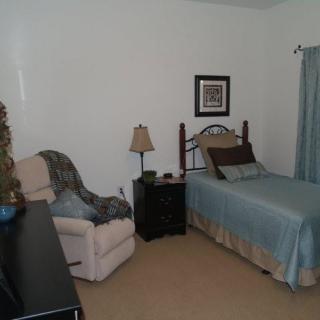 A cozy bedroom with a bed, chair, and nightstand.