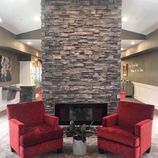 A cozy living room featuring a stone fireplace flanked by two red armchairs.