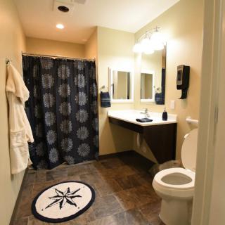 A well-lit bathroom with a shower curtain, sink, mirror, and toilet.