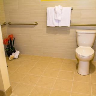 An accessible bathroom with a toilet, grab bars, and folded towels.