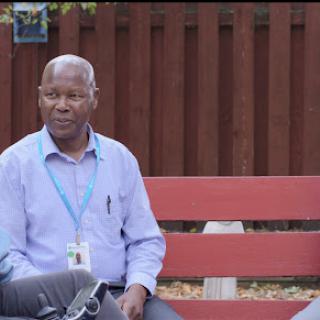 A man sitting on a bench in an outdoor setting.