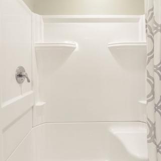 A modern, clean white shower space with built-in shelves.