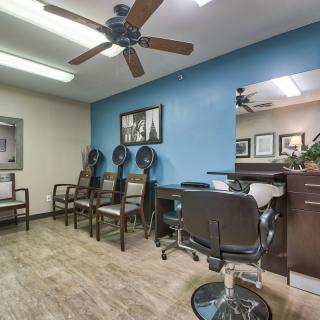 Hair salon interior with chairs, hair dryers, and a blue accent wall.