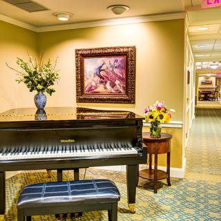A cozy interior featuring a piano, floral arrangements, and artwork.