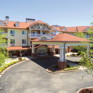 A front view of a hotel with a circular driveway and well-maintained landscaping.