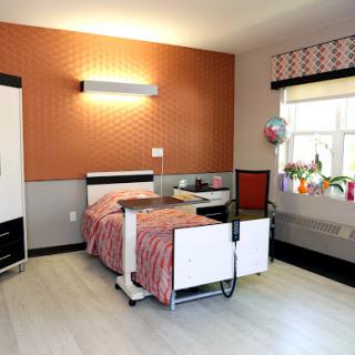 A well-designed hospital patient room featuring modern furnishings and a bright window.