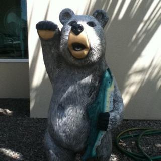 A bear statue holding a fish, located outdoors.
