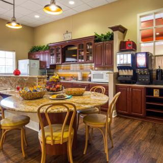 A cozy kitchen with wooden cabinets and a round dining table, complemented by warm lighting.