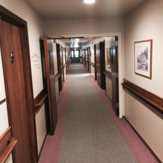 A well-lit hallway with multiple doors on either side, resembling a hotel corridor.