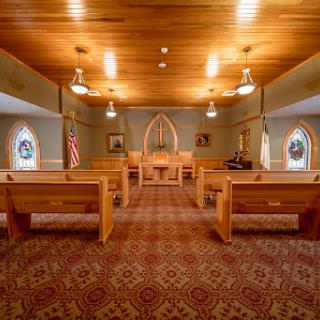 A peaceful interior view of a church, featuring wooden pews and soft lighting.