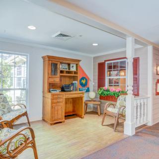 A cozy home office space with a wooden desk, chairs, and decorative elements by the window.