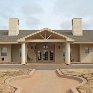 A symmetrical building with a prominent entrance featuring columns and a gabled roof.