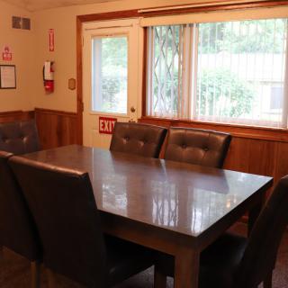 A dining room with a table and chairs by a window.