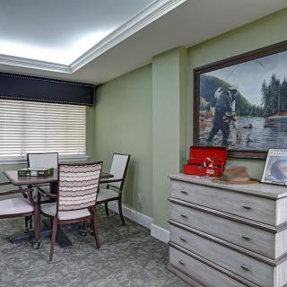 A modern dining area with a table, chairs, and a dresser adorned with decorative items and a large painting on the wall.