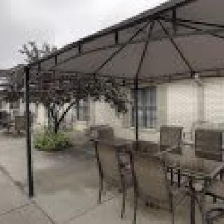 An outdoor patio setup with a gazebo, table, and chairs.