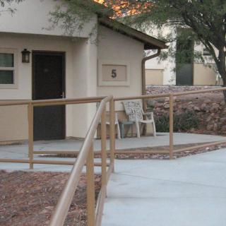 A house with a ramp and chairs on the porch.
