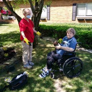 A caregiver assists a person in a wheelchair while enjoying some time outdoors.