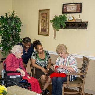 A group of people gathered in a care facility, engaging in a social activity.