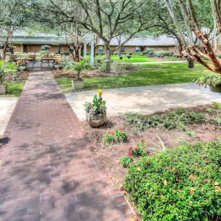 A scenic garden with a pathway, surrounded by lush greenery and benches.