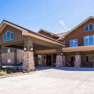 A modern residential building with stone pillars and a wide driveway.