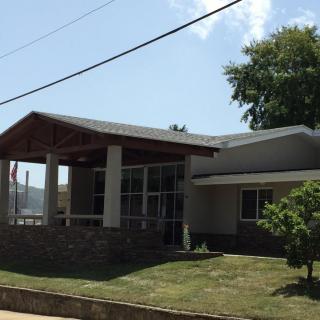 A residential house with a porch and front yard on a sunny day.