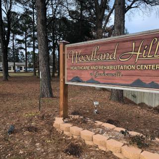 A sign for Woodland Hills, set against a backdrop of trees and nature.