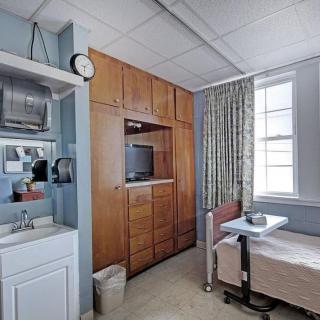 A hospital room with a patient's bed, television, and basic amenities.