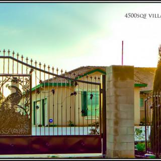 A view of a house behind an ornate gate at sunset.