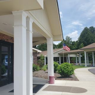 A sunny view of a building entrance with an American flag displayed.