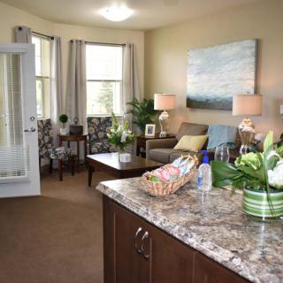 A cozy living room with comfortable seating, artwork on the wall, and decorative plants.