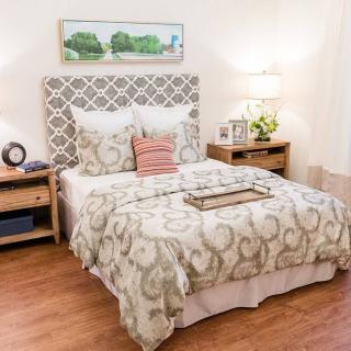 A cozy and well-decorated bedroom with a patterned headboard and matching bedding.