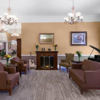 A cozy lounge area featuring comfortable seating, elegant chandeliers, and a classic fireplace.