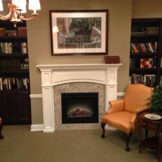 A cozy reading corner featuring a fireplace surrounded by bookshelves and a comfortable armchair.