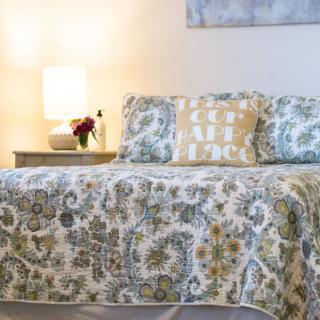 A cozy bedroom setup with patterned bedding and a softly lit lamp on the nightstand.