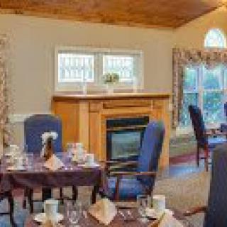 A cozy dining room with a fireplace and neatly arranged tables and chairs.