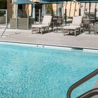Outdoor swimming pool with lounge chairs and umbrellas.
