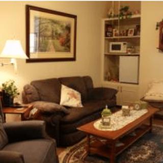 A cozy living room with a sofa, armchair, coffee table, and warm lighting.