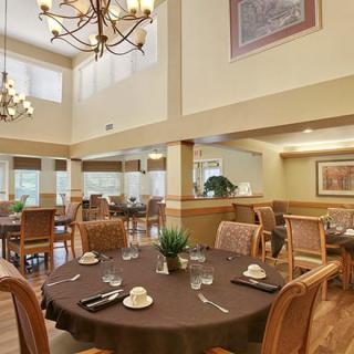 A spacious and elegant dining room with well-arranged tables, chairs, and chandeliers.