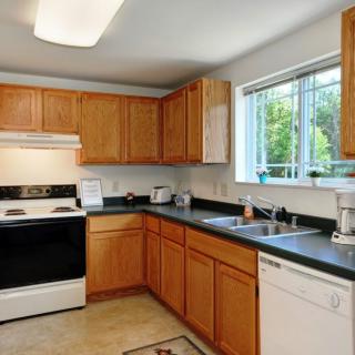 A modern kitchen with wooden cabinets, a stove, and a window above the sink.