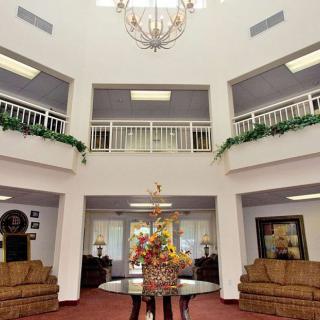 A spacious lobby with a chandelier, sofas, and decorative flowers.