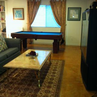 A cozy living room featuring a billiard table, a comfortable sofa, and a decorative rug.