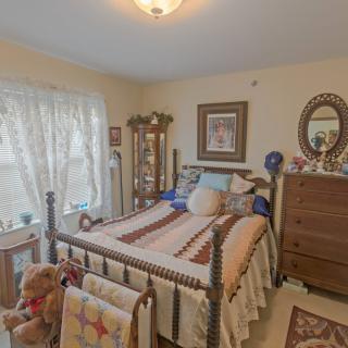 A cozy bedroom featuring a quilt-covered bed and wooden furniture.