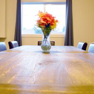 A dining table with a vase of colorful flowers near a window.