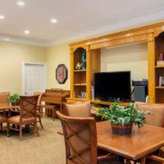 A cozy living room featuring a dining area, television, and wooden shelves adorned with plants.