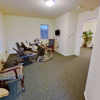 A small exercise room with fitness equipment, seating, and a television.