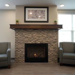 A cozy living room featuring a modern fireplace, stylish seating, and decorative elements.
