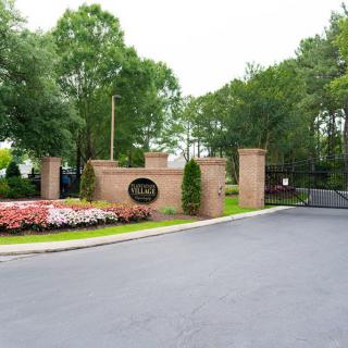 Entrance to a gated community with a brick wall, landscaped flowers, and trees.