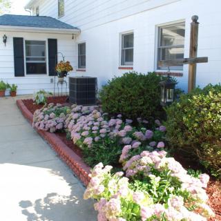 A neatly landscaped garden featuring various flowers and bushes alongside a house.