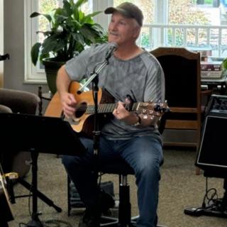 A man playing an acoustic guitar while singing indoors.