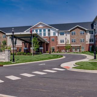 A modern residential building with well-maintained landscaping and a curving driveway.